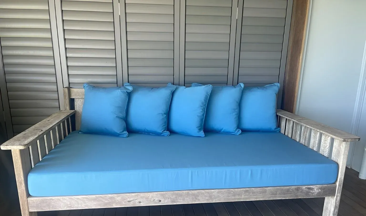 Wooden Couch With Blue Pillows is in Front of a Wall With Shutters — Dennys Upholstery & Outdoor Blinds In Ballina, NSW