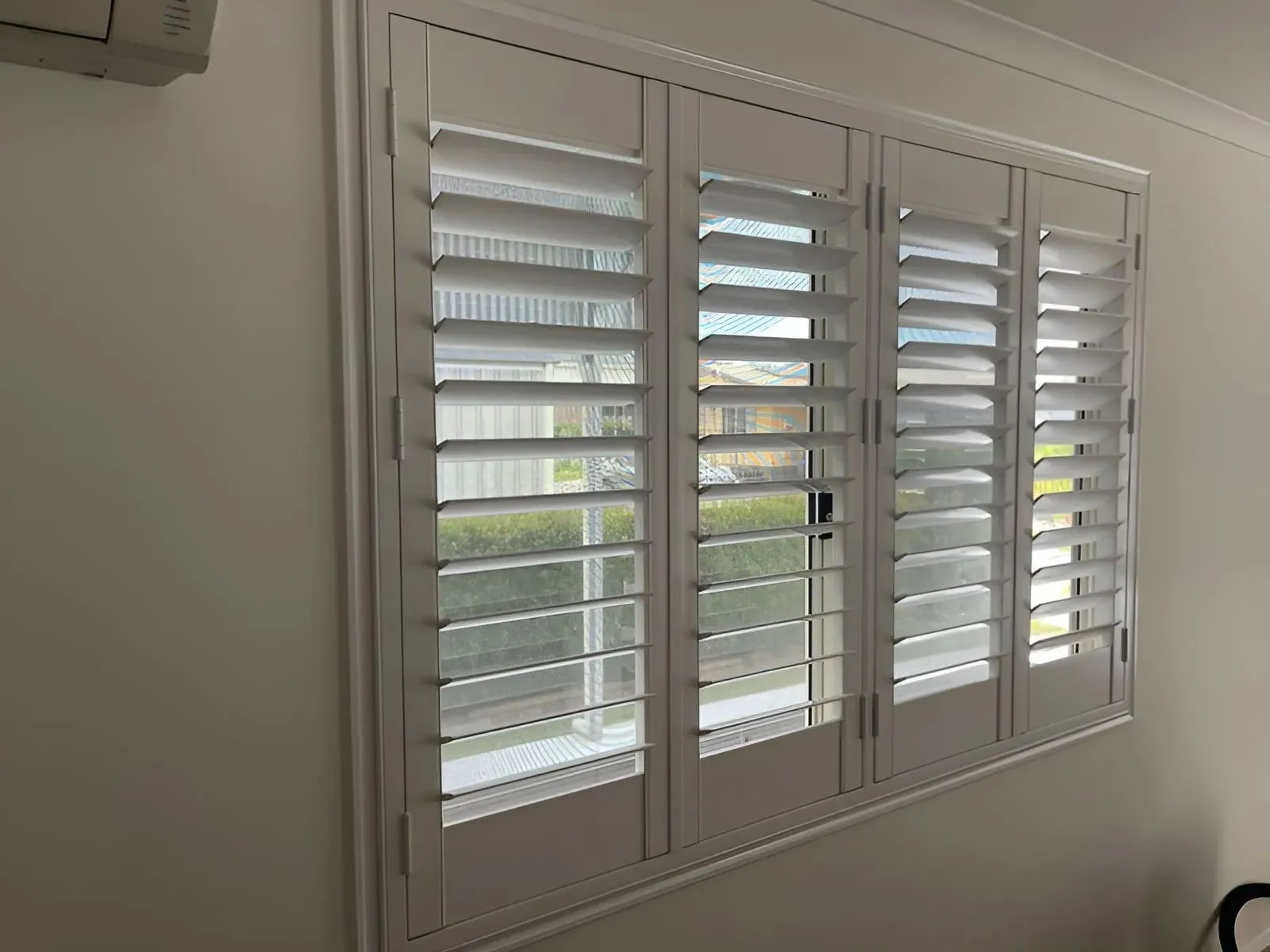 A Window With White Shutters on It in a Room — Dennys Upholstery & Outdoor Blinds In Ballina, NSW