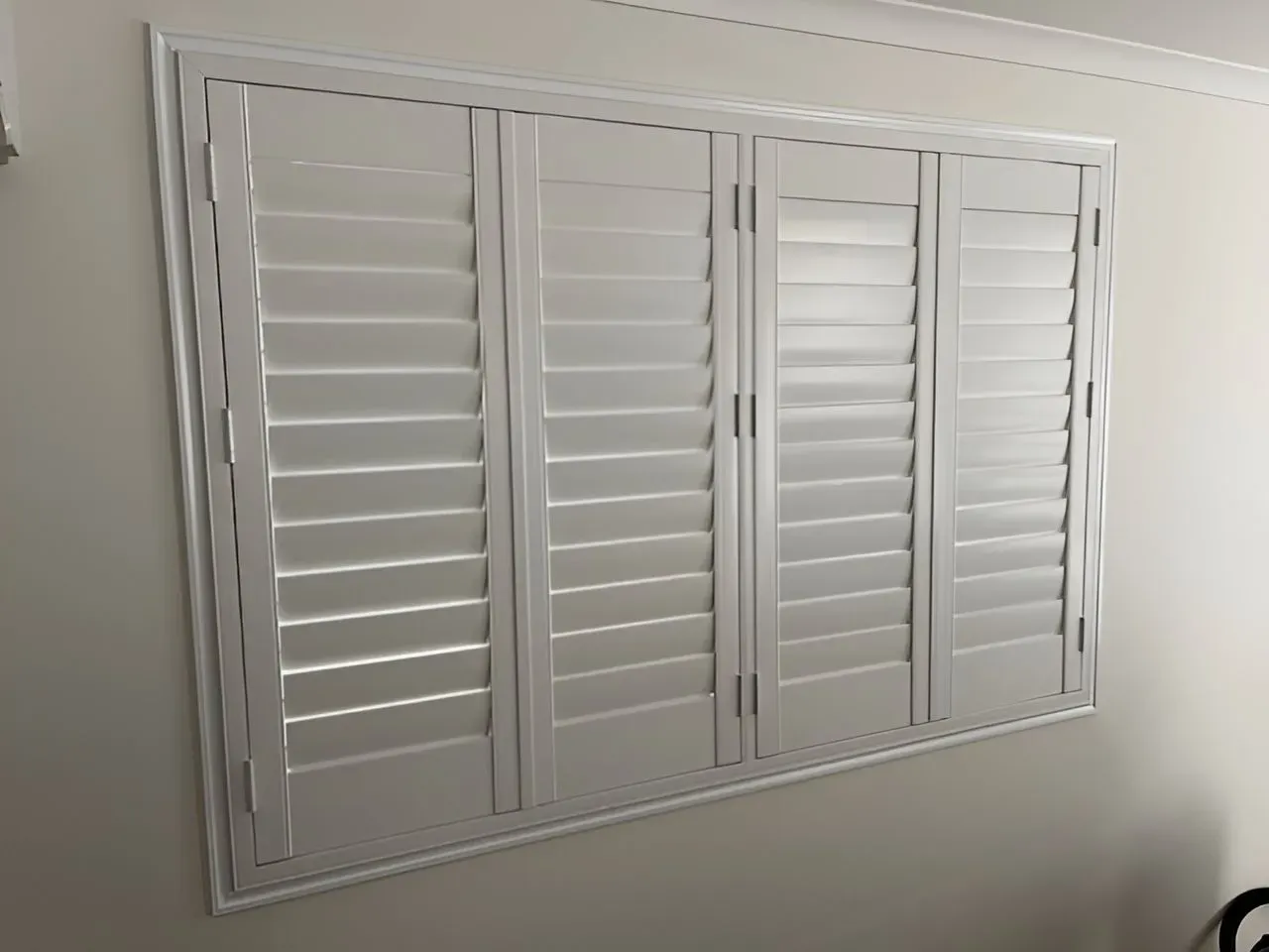 A Window With White Shutters on It in a Room — Dennys Upholstery & Outdoor Blinds In South Lismore, NSW