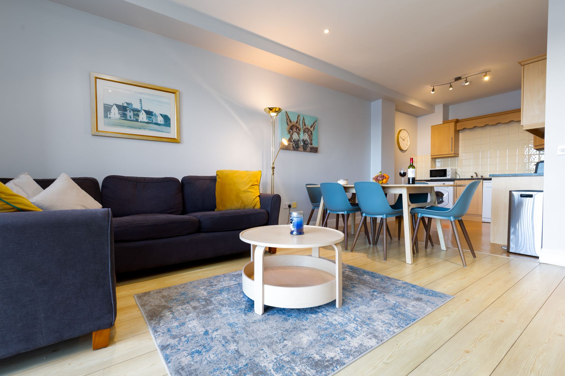 Open-plan living space with a blue sofa, dining area, and a light wooden floor.