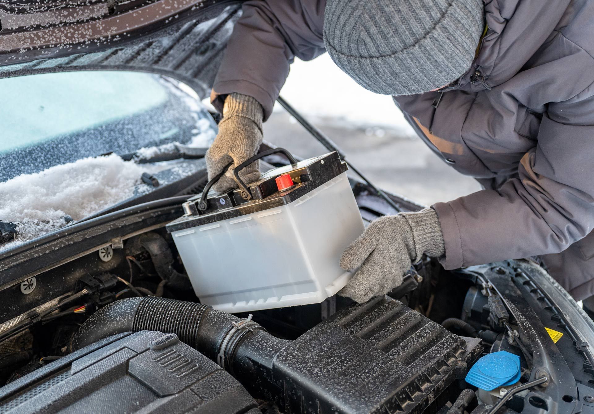 Person in gloves filling a car with fluid from a container in snowy weather