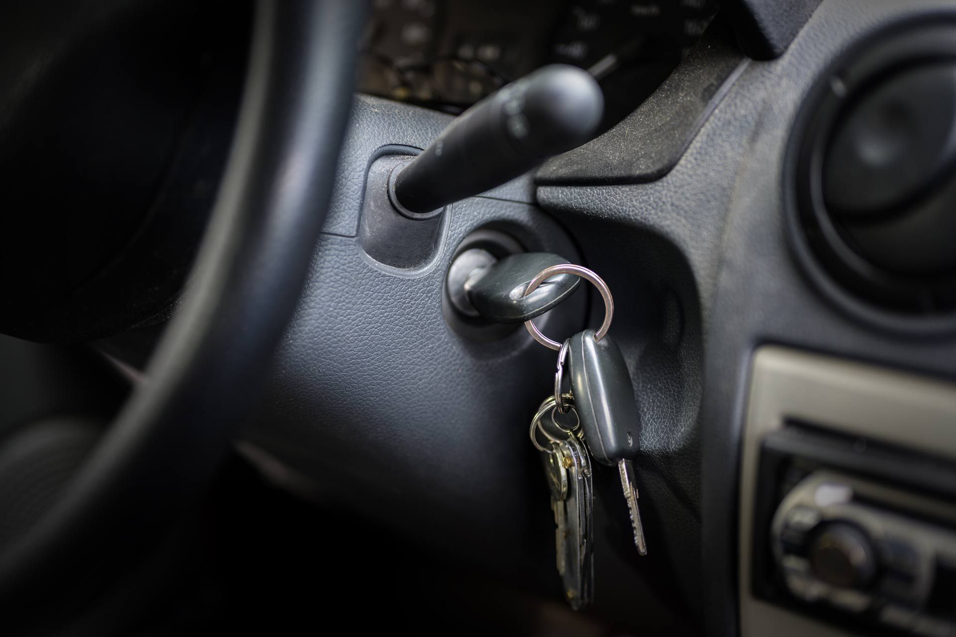 Car keys in a car ignition with the dashboard and steering wheel visible.