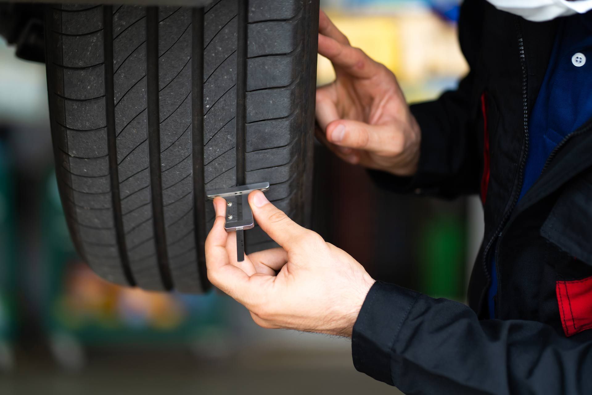 Mechanic measuring a car tire tread with a gauge in a garage