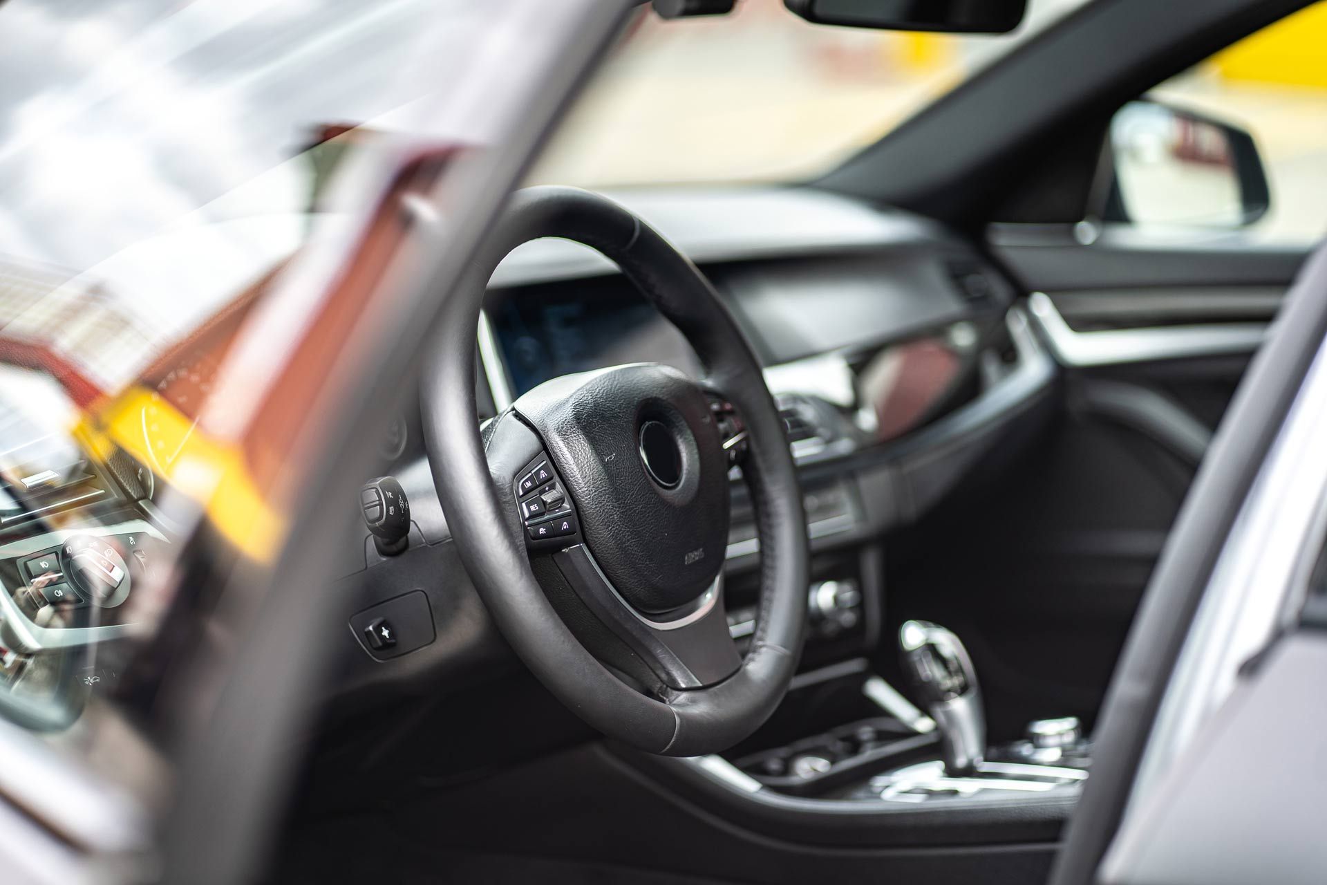Car interior with black steering wheel, dashboard, and center console in a modern vehicle