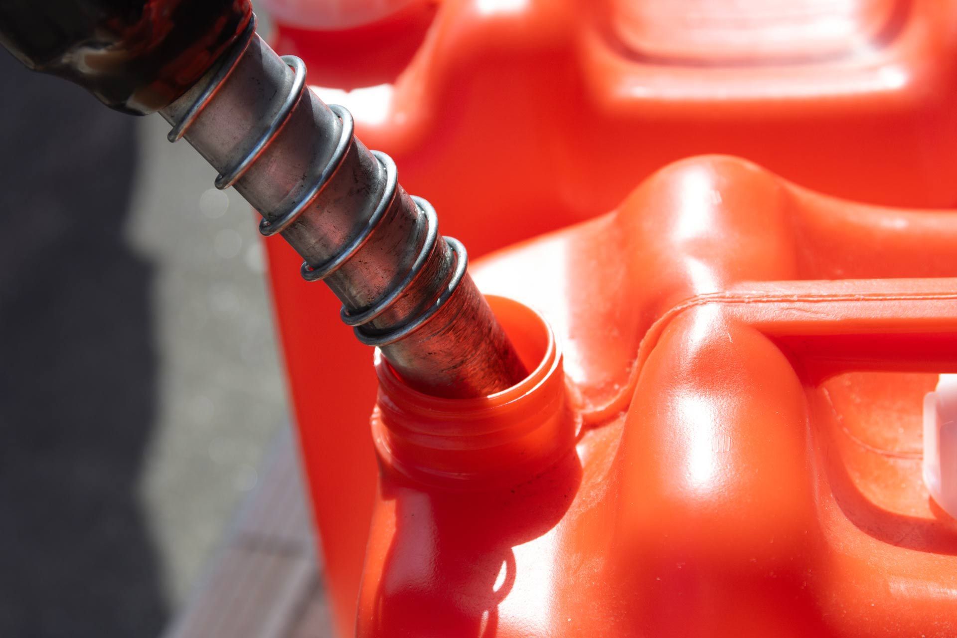Fuel nozzle filling a red plastic container at a gas station