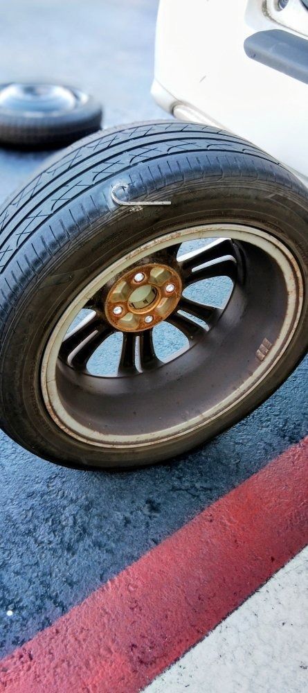 Close-up of a car tire and wheel on pavement beside a red curb line.