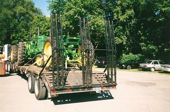 A trailer with a green john deere tractor on it