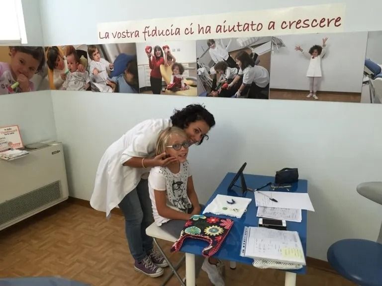 Un medico visita un bambino in una clinica, con poster educativi alle pareti.