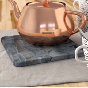 A copper tea kettle sits on a marble cutting board