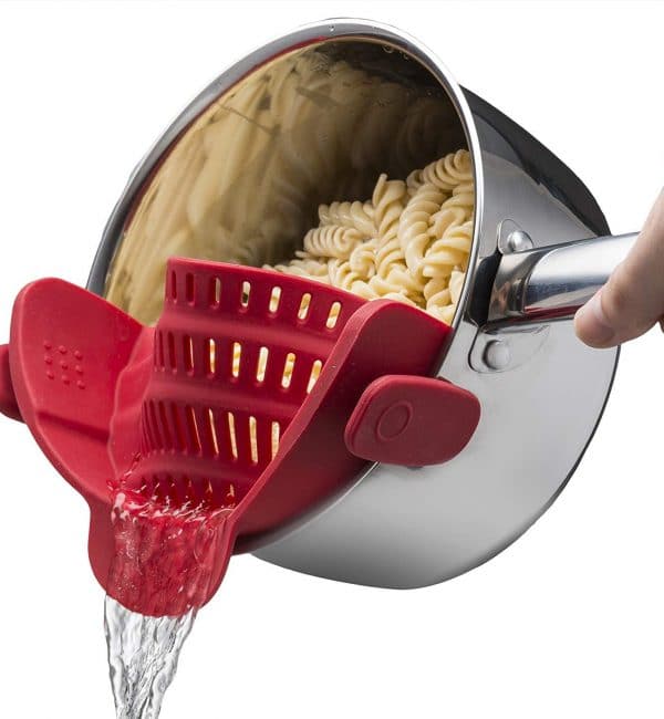 A person is pouring water into a pot of pasta