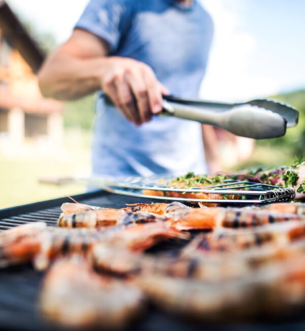 A man is cooking food on a grill with tongs