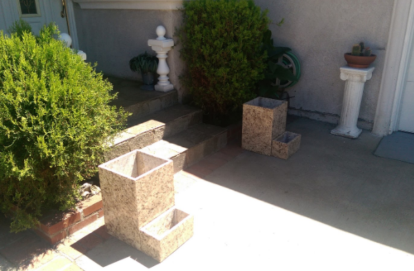 A patio with a fountain and planters in front of a house