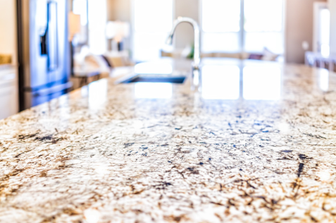 A close up of a granite counter top in a kitchen with a sink.