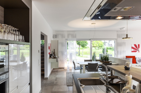 A kitchen with a sink and a dining room in the background