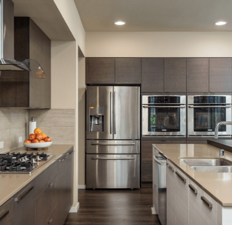 A kitchen with stainless steel appliances and a bowl of oranges on the counter