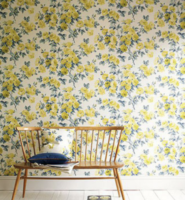 A wooden bench in front of a floral wallpaper