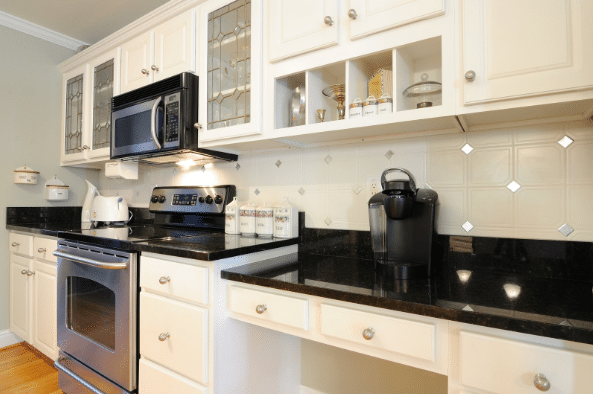 A kitchen with white cabinets and black counter tops