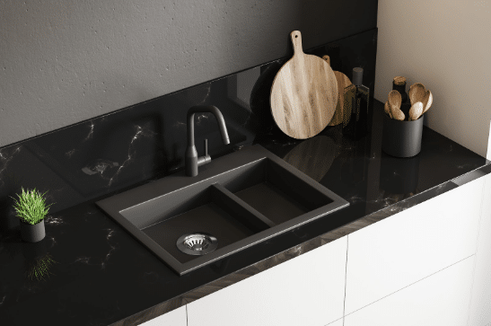 A kitchen sink is sitting on top of a black counter.