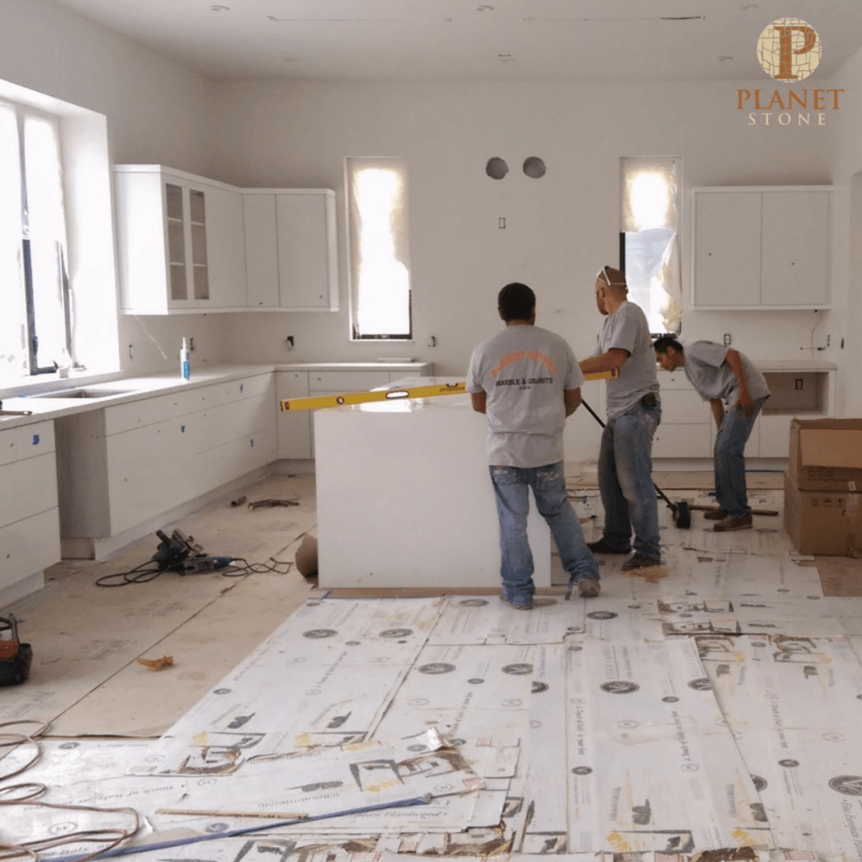 A group of men are working in a kitchen with a plant studio logo on the ceiling