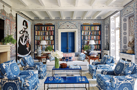 A living room filled with blue and white furniture and bookshelves.