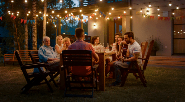 A group of people are sitting around a table in a backyard at night.