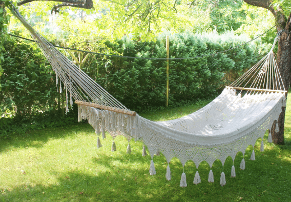 A white hammock is sitting on top of a lush green lawn.