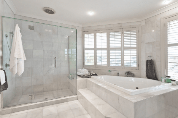 A bathroom with a tub , shower , and window.