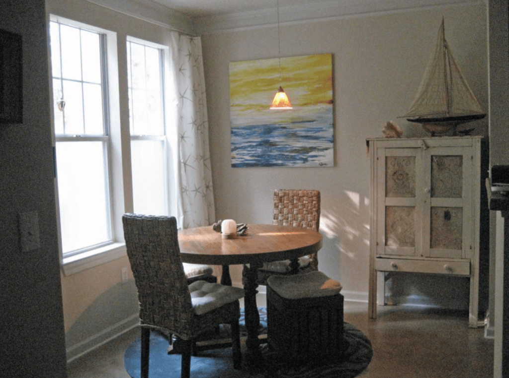 A dining room with a table and chairs and a painting on the wall