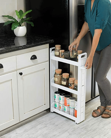 A woman is pulling a spice rack out of a refrigerator.