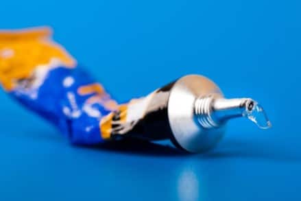 A tube of glue is laying on a blue surface.