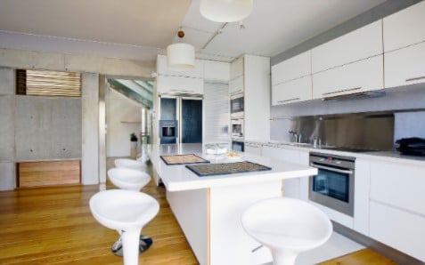A kitchen with white cabinets and stools and a large island