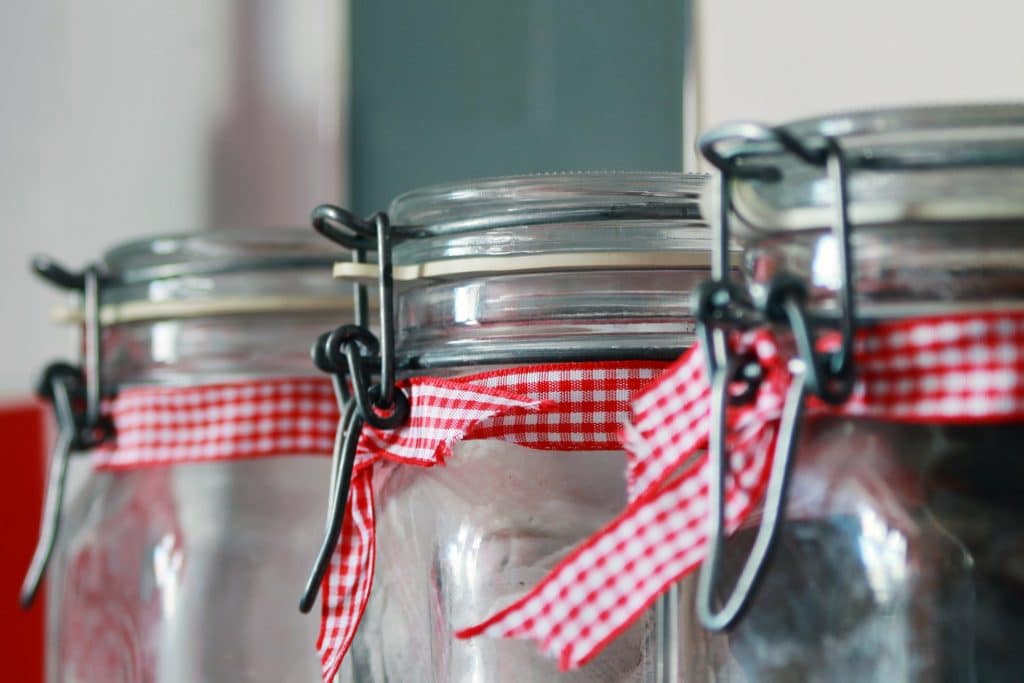 Three glass jars with red and white checkered ribbons on them.