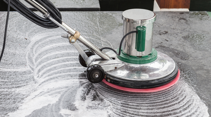 A person is using a machine to clean a tile floor.