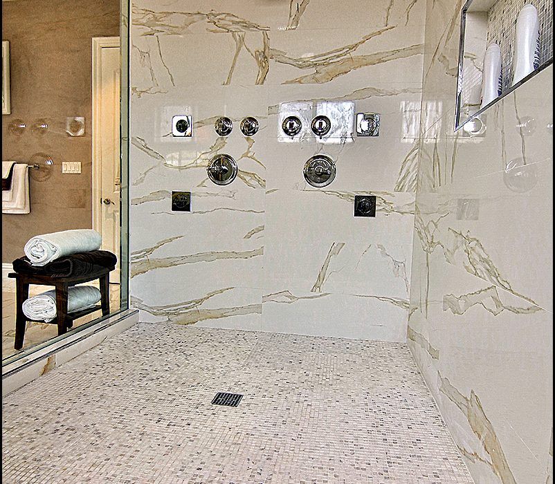A bathroom with marble walls and a walk in shower