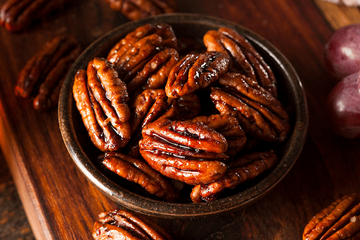 A bowl of pecans is sitting on a wooden table.