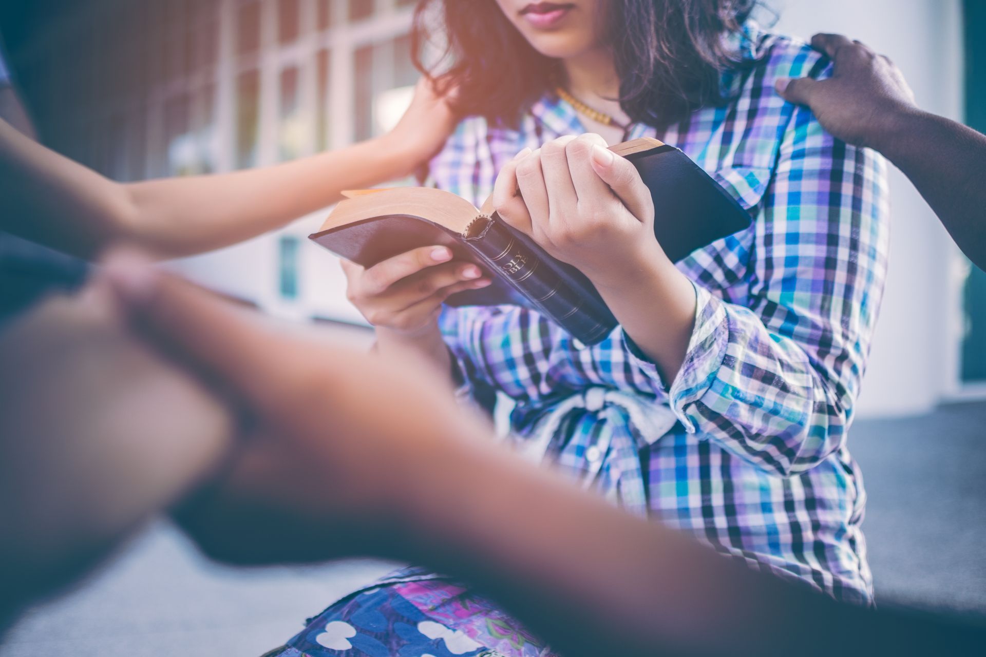 Person holding a book outdoors while another person reaches toward it