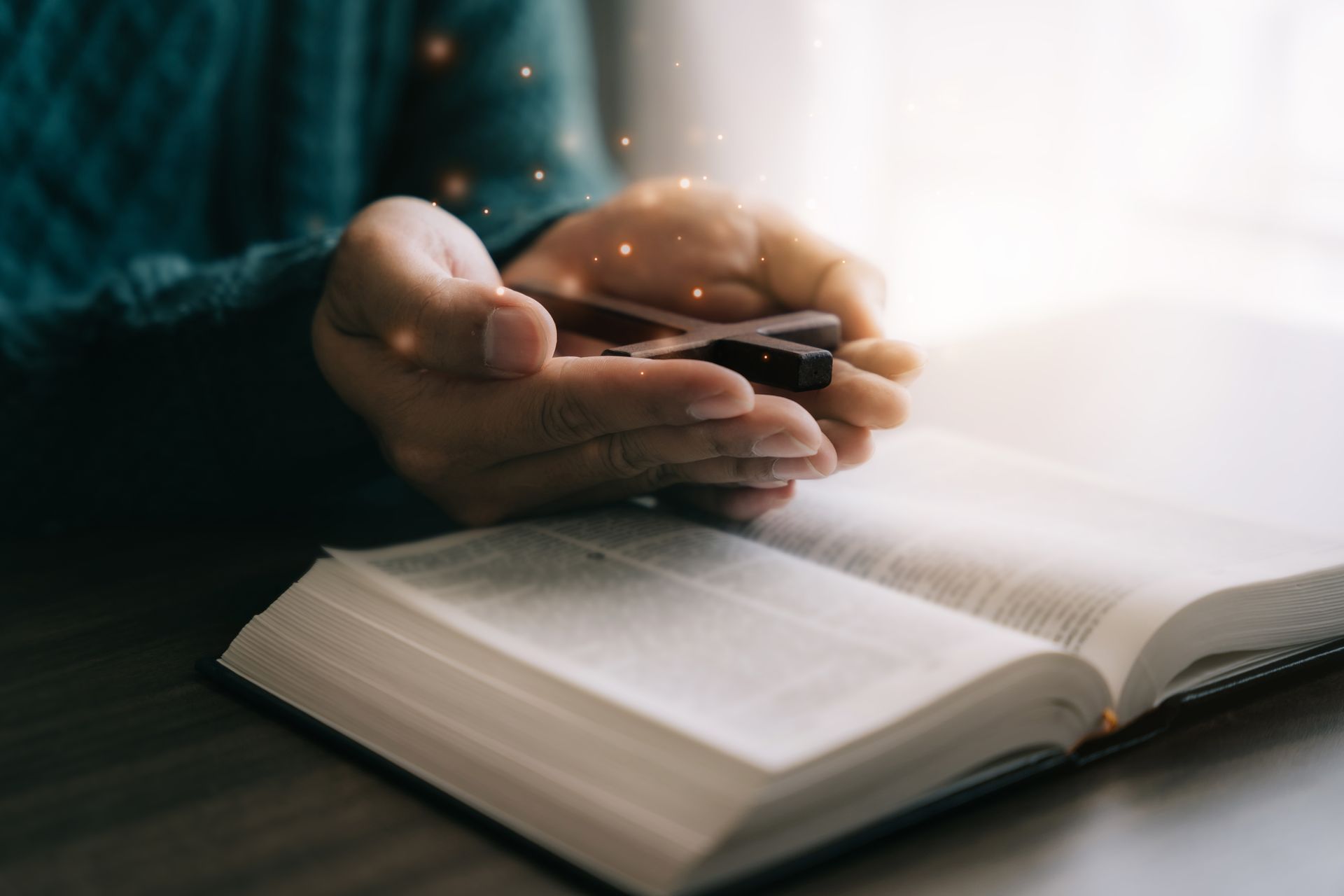 Hands holding a smartphone above an open book in warm light