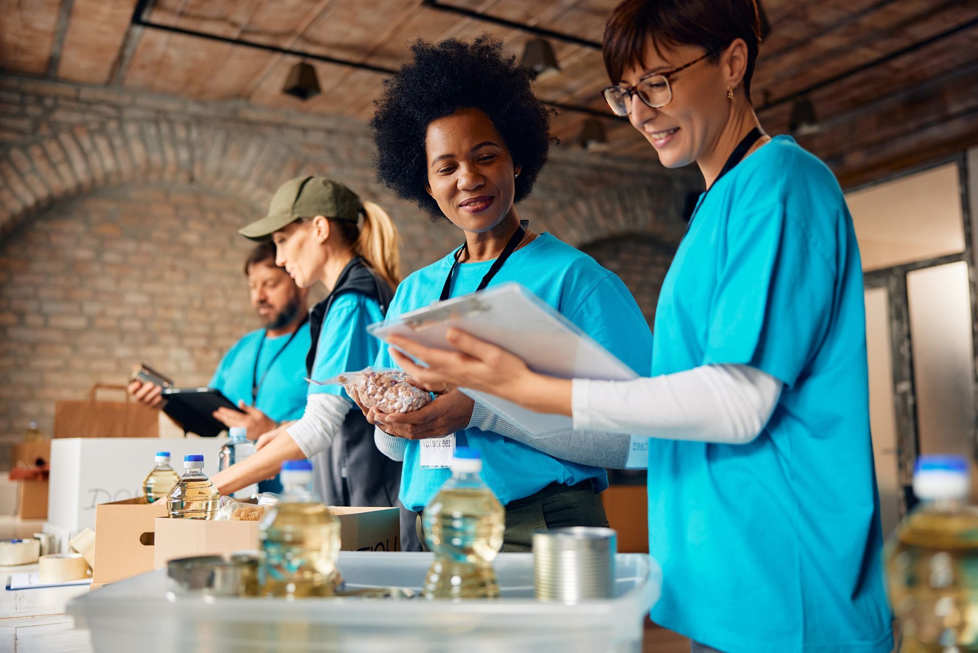 People in blue shirts handling food samples at a table in a rustic indoor setting