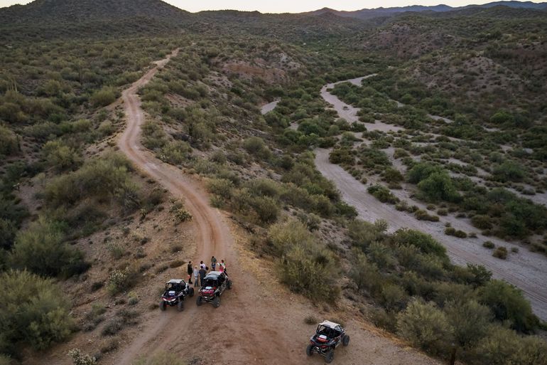 A group of people are riding atvs down a dirt road in the desert.