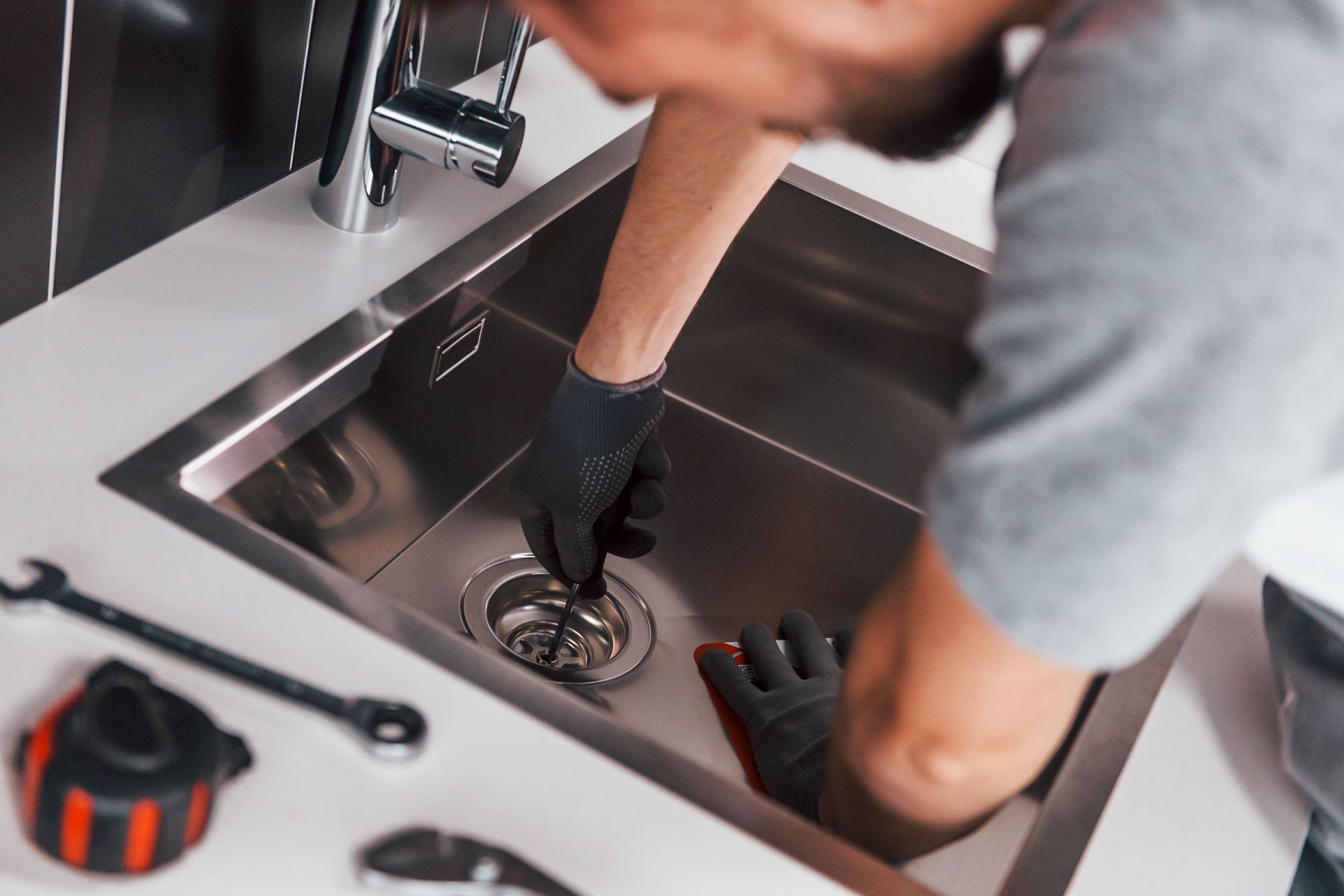 Residential plumber clearing clogged kitchen sink drain.