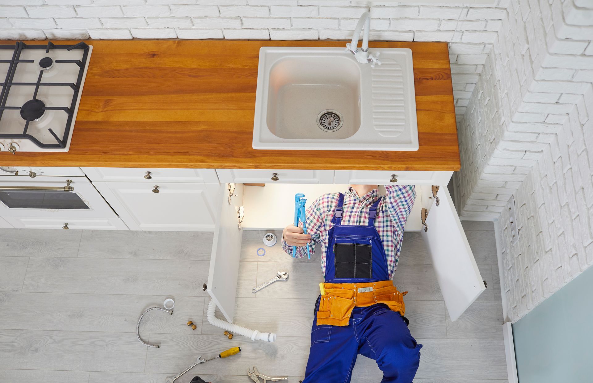 A residential plumber repairing pipes under the kitchen sink.