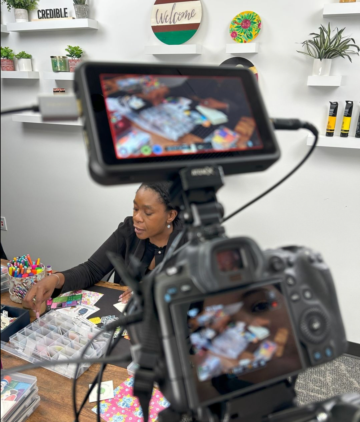 Behind-the-scenes shot of a video production capturing a close-up of an artist journaling with a pen on a notebook.