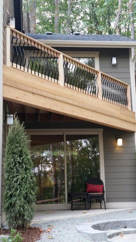 A two-story house with a wooden deck and a sliding glass door. A chair sits on the patio.