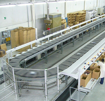 Cinta transportadora de una fábrica con cajas de cartón moviéndose a través de un almacén limpio.