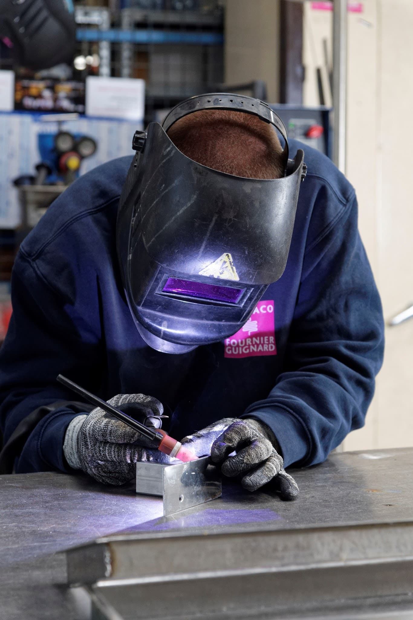 Un homme portant un casque de soudage soude un morceau de métal.