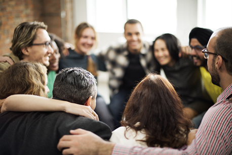 A group of people are sitting in a circle hugging each other.