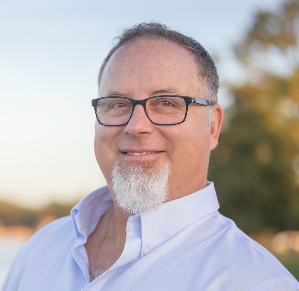 A man with glasses and a beard is smiling for the camera