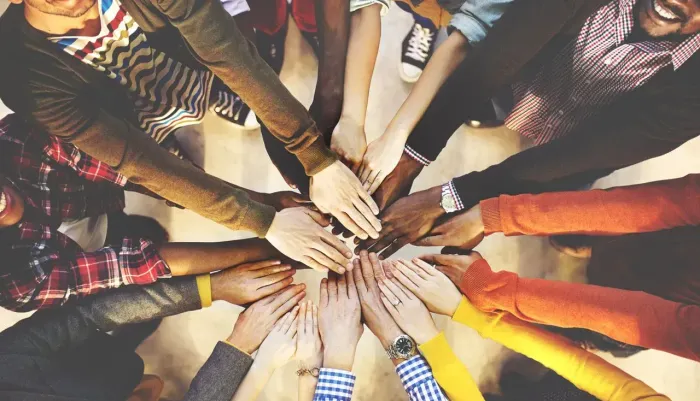 A group of people are putting their hands together in a circle.