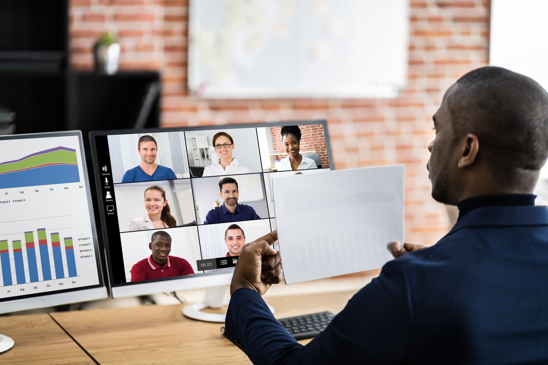 A man is holding a piece of paper in front of a computer screen while having a video call.