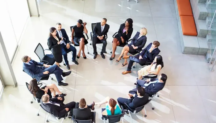 A group of business people are sitting in a circle in an office.